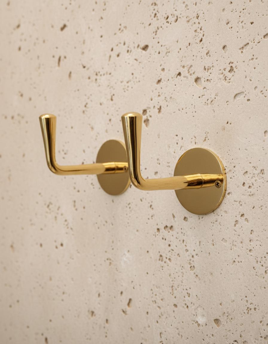 Gold double hook on a beige speckled wall