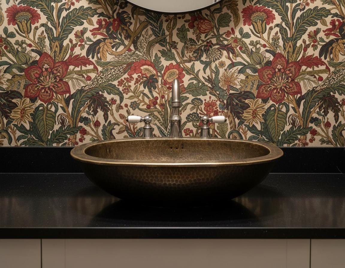 Bronze sink with floral-patterned wallpaper in a bathroom setting
