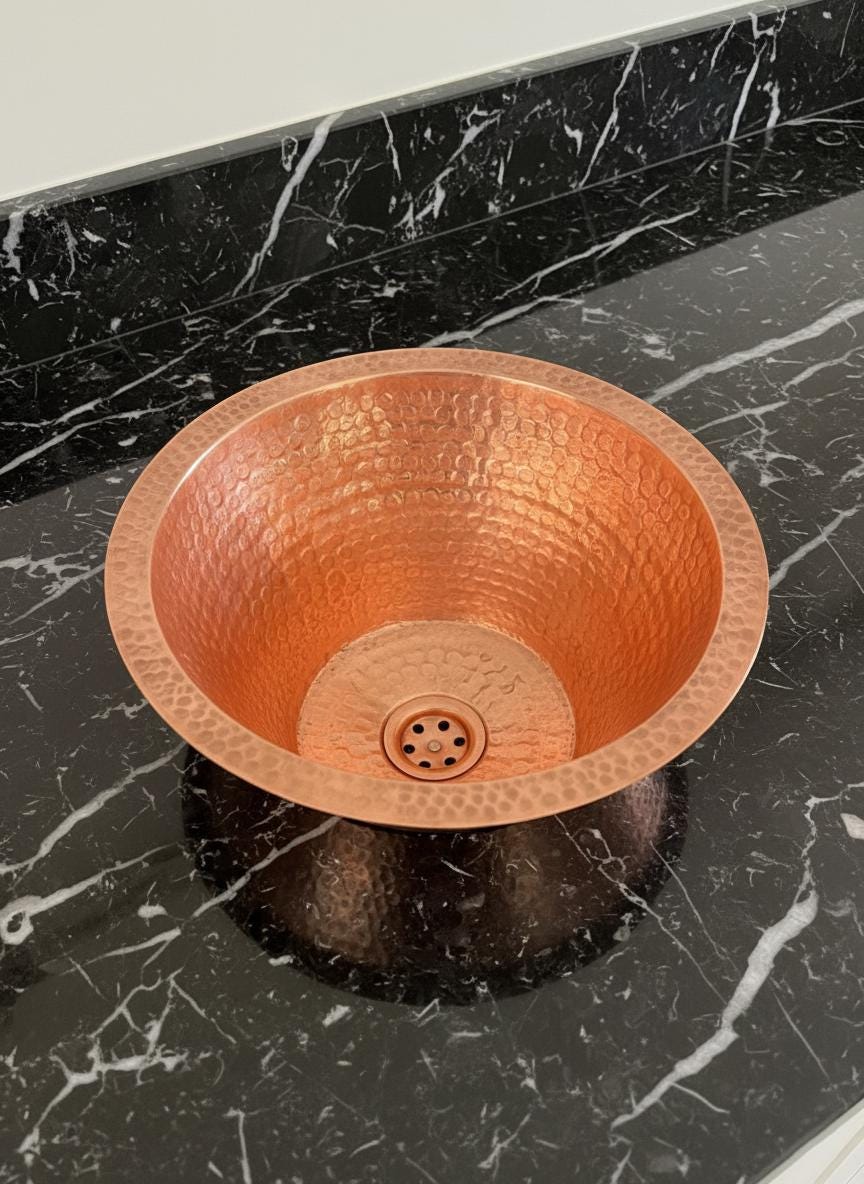 Copper sink on a black marble countertop