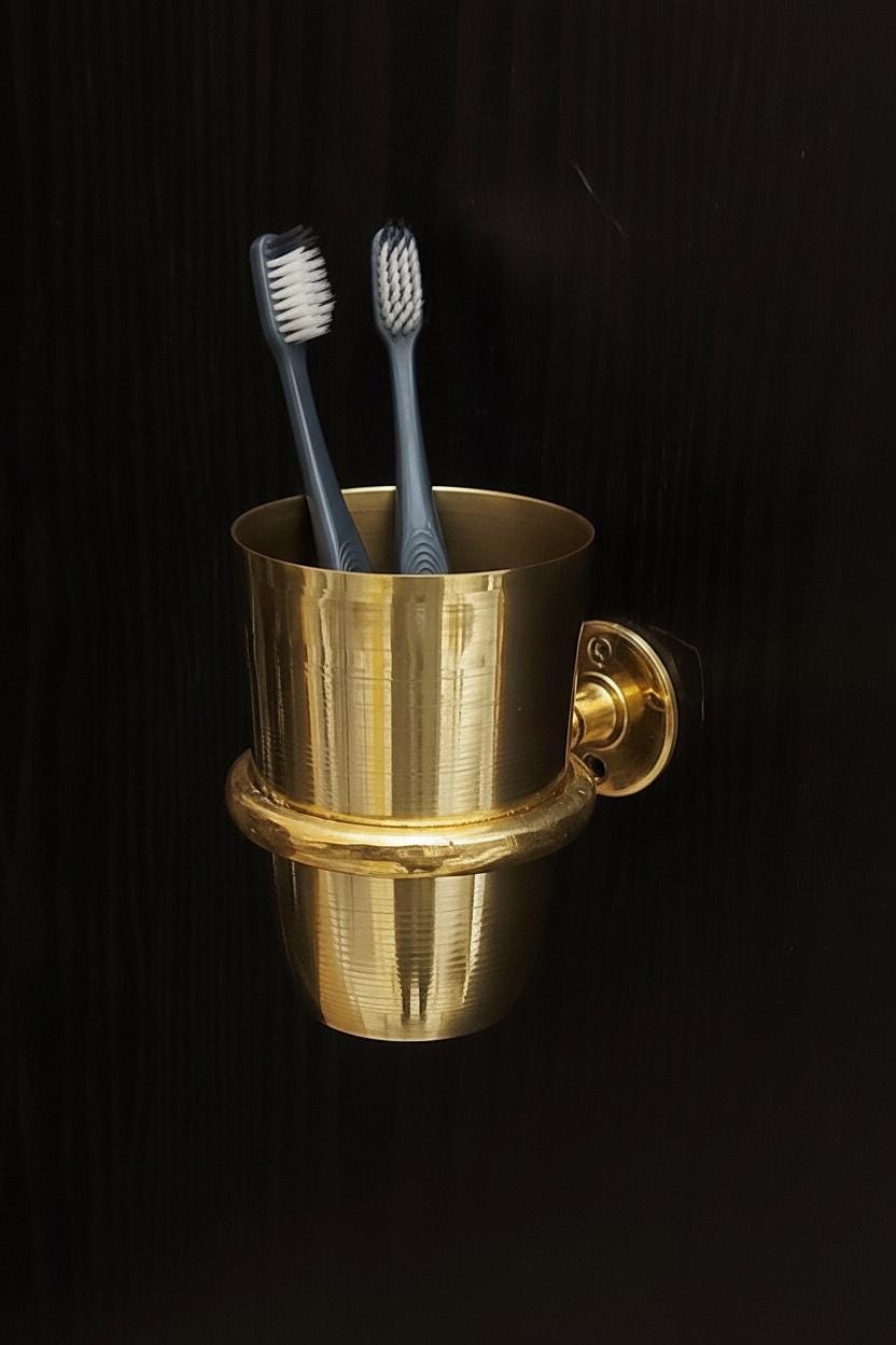 Brass toothbrush holder with two toothbrushes on a black background