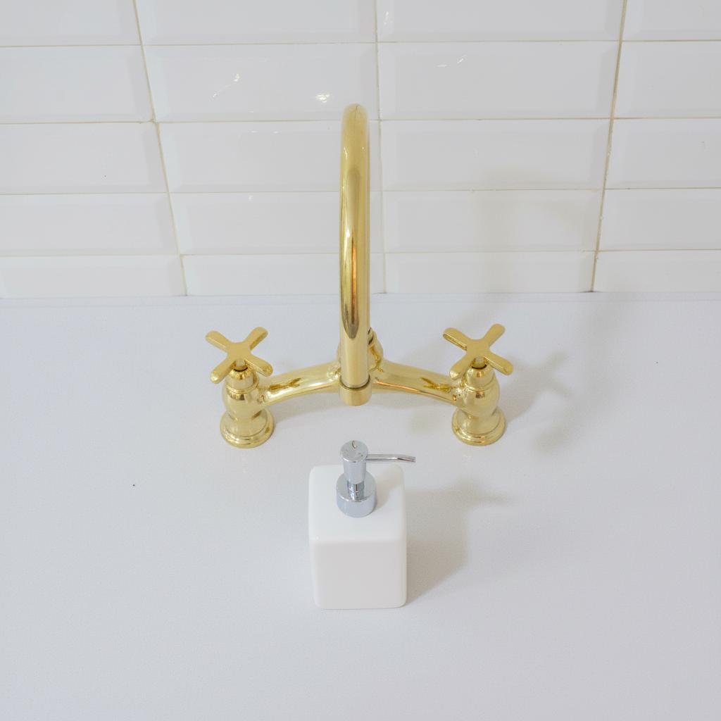 Gold faucet and handles on a white tiled wall