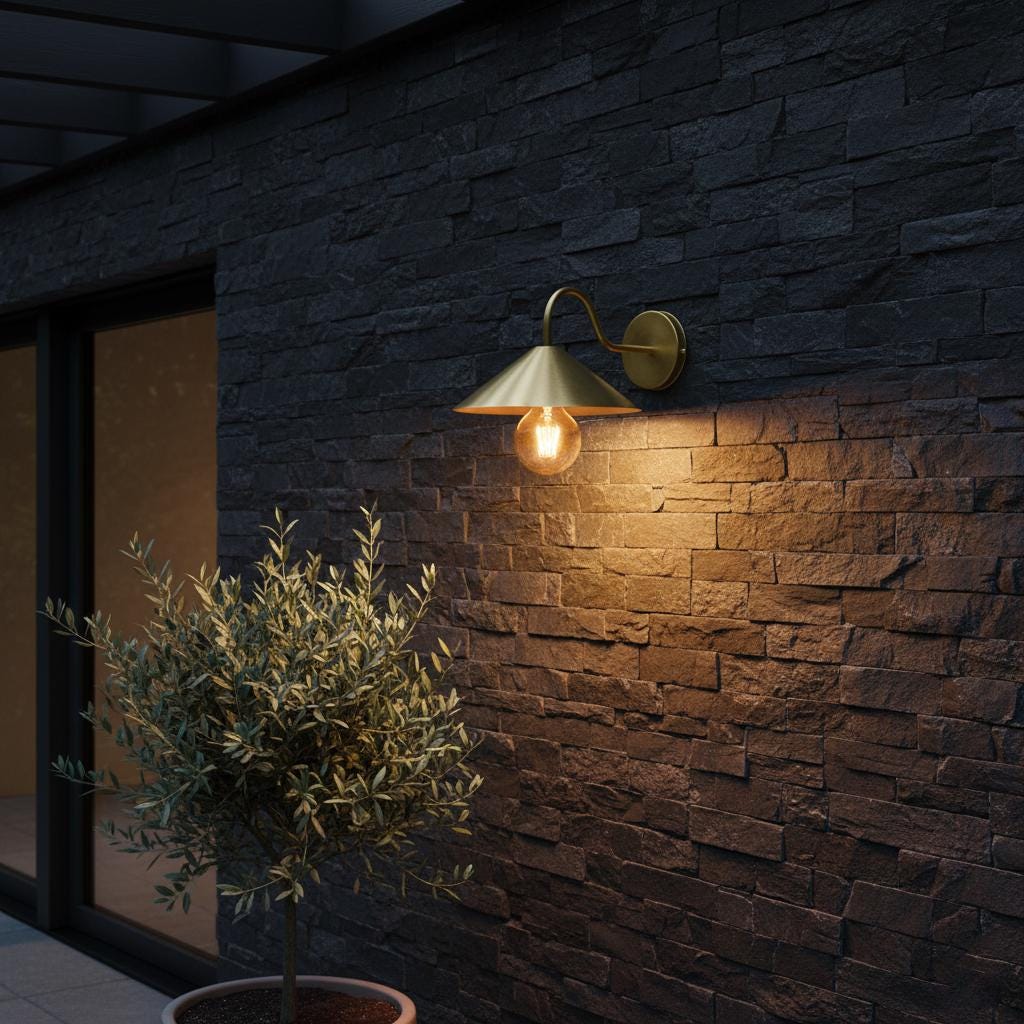 Wall-mounted outdoor light fixture on a stone wall with a potted plant nearby.
