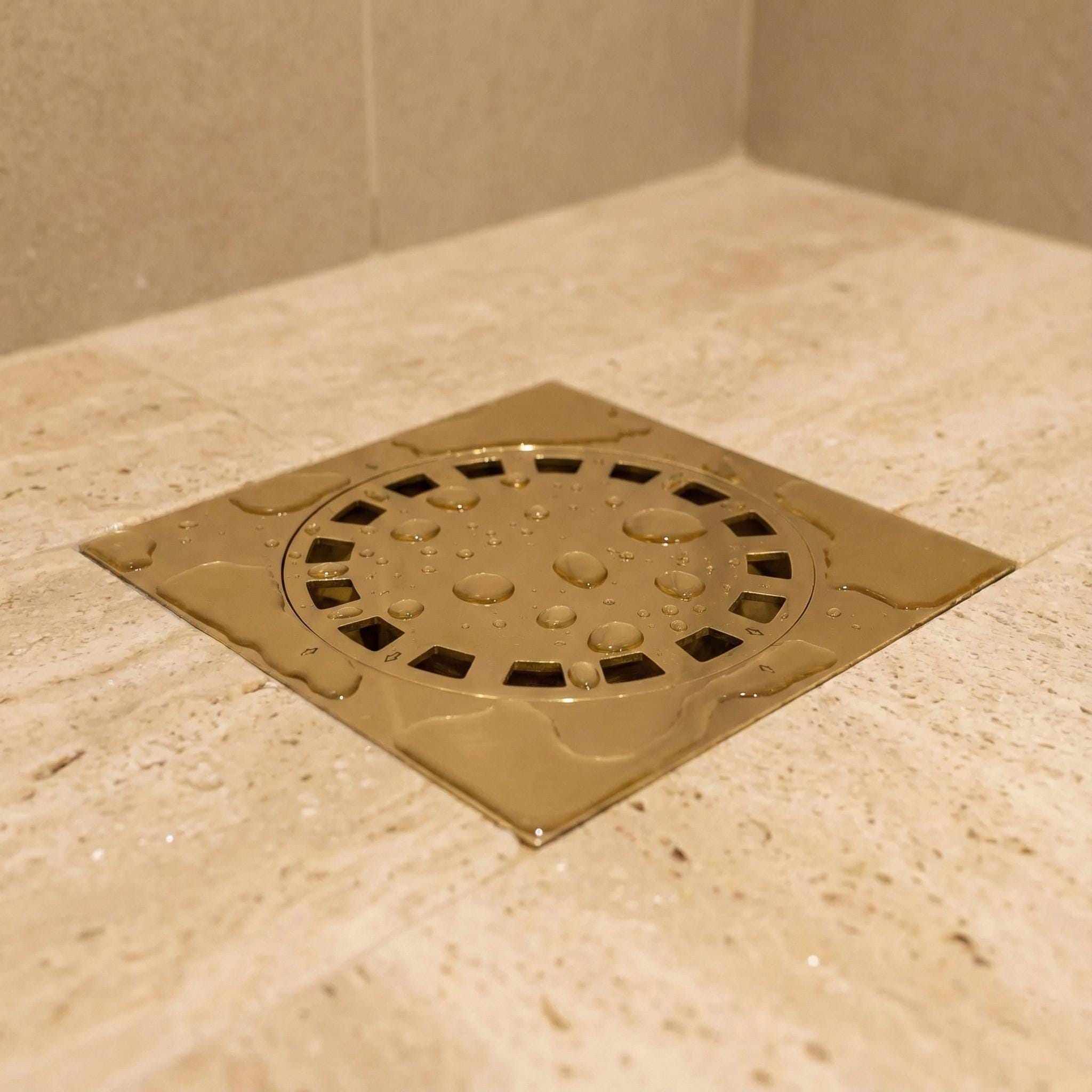 Metallic shower drain cover on a tiled bathroom floor