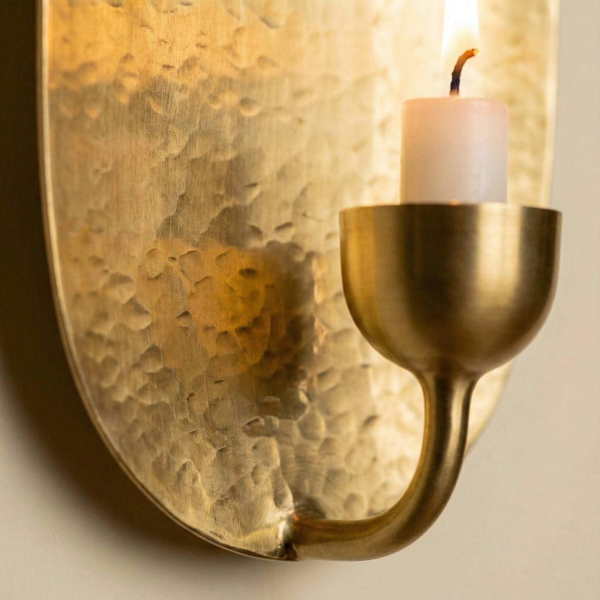 Brass wall sconce with a candle on a neutral background