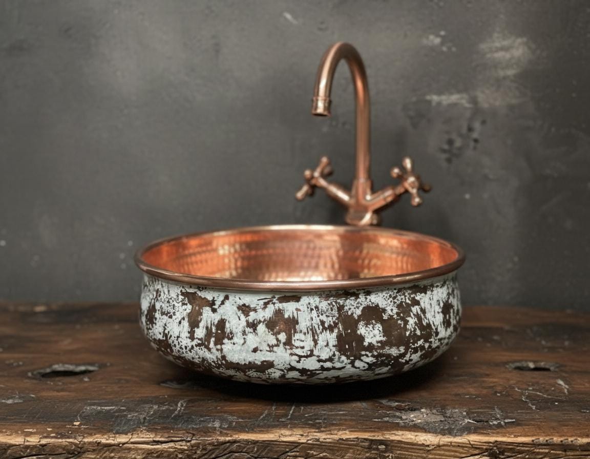 Copper sink with faucet on a wooden surface against a dark background