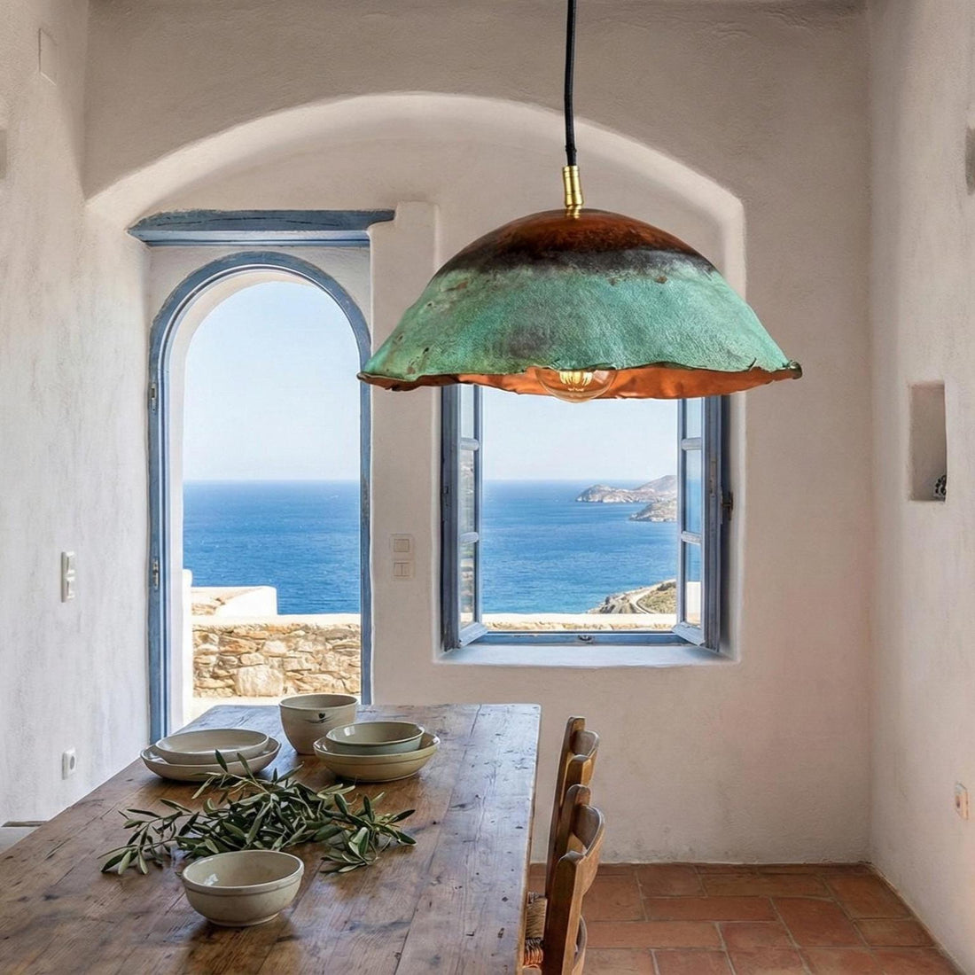 Pendant light with a scenic view of the ocean through an open window.