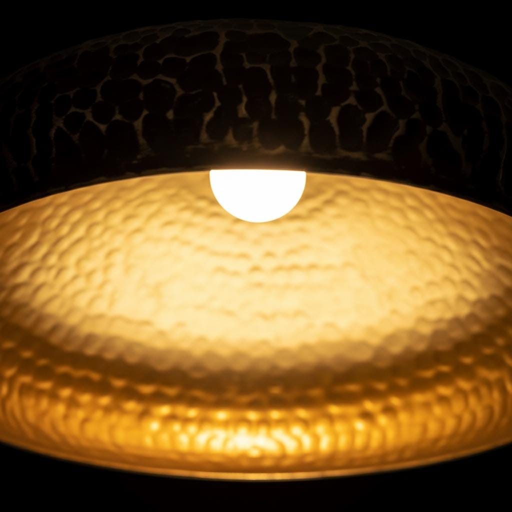 Close-up of a textured ceiling light fixture with a bulb inside on a black background