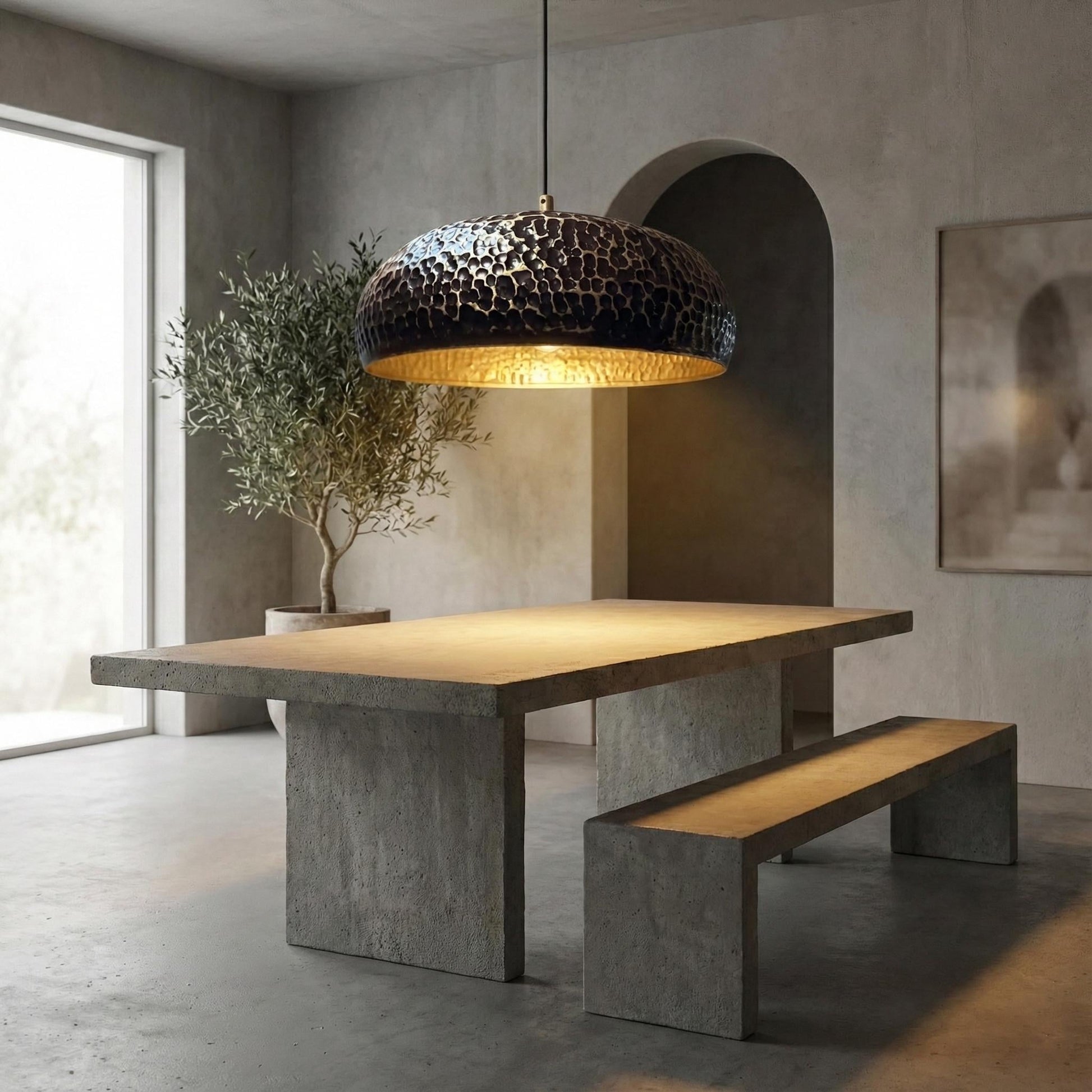 Modern dining area with concrete table and bench, featuring a decorative pendant light.