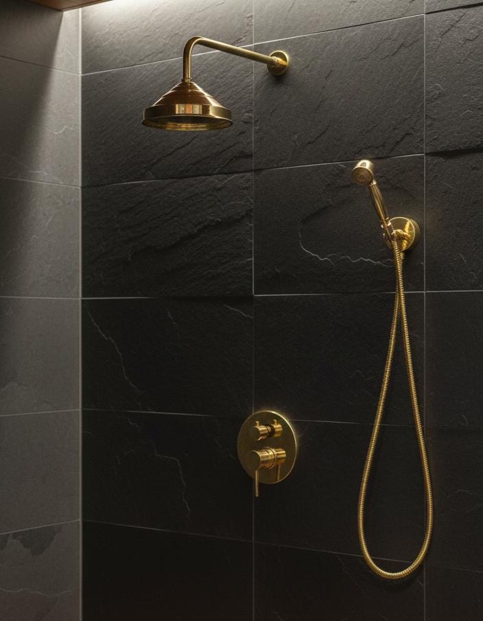 Gold shower head and control valve on a dark tiled wall
