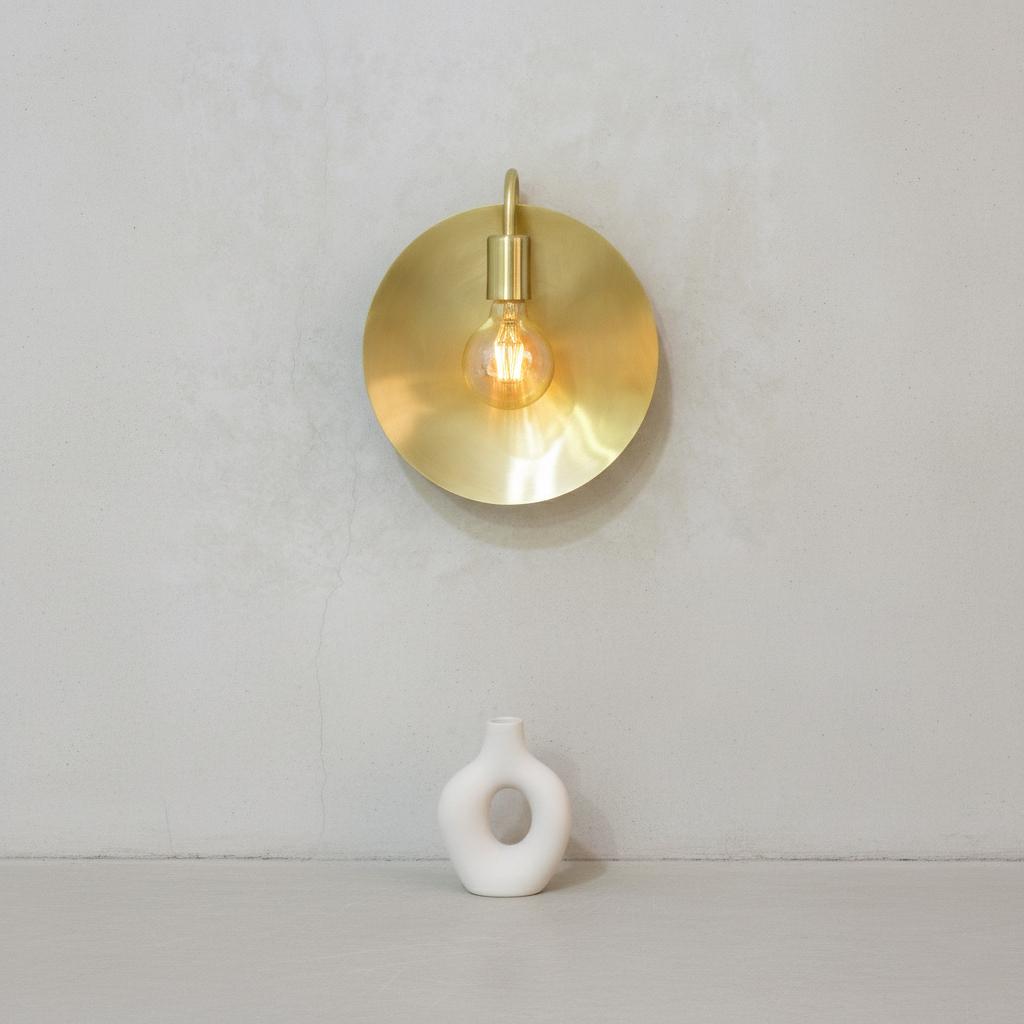 Brass wall sconce with a light bulb on a plain white background