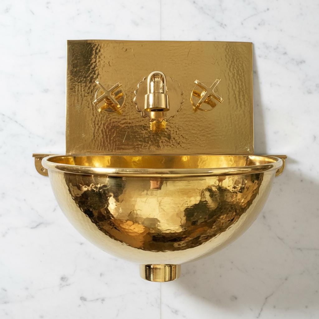 Gold wall-mounted sink with decorative elements on a white marble background
