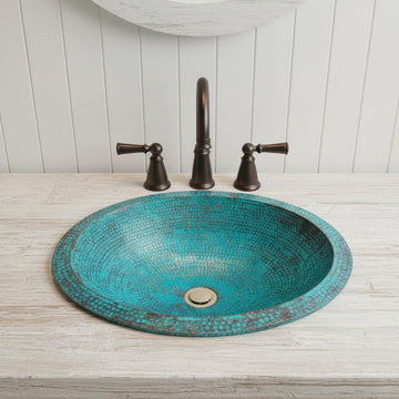 copper sink with bronze faucet and handles on a wooden countertop.