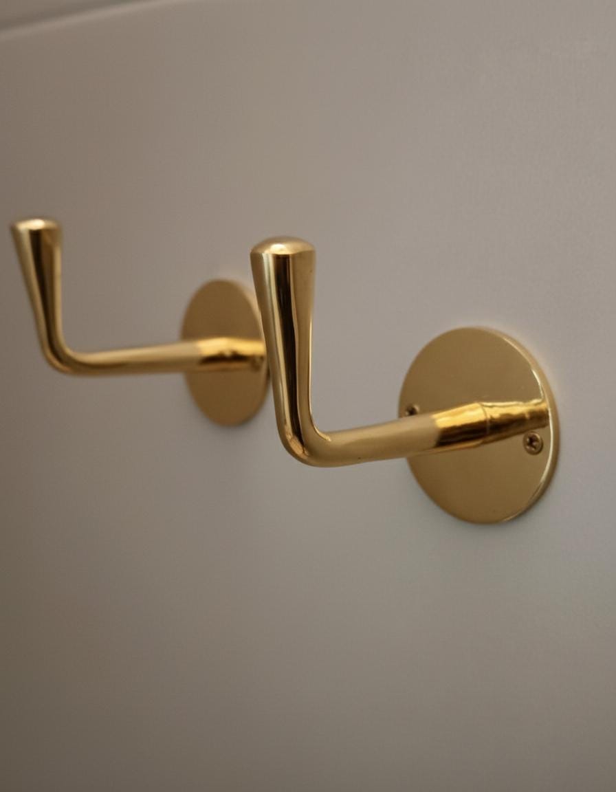 Two gold hooks on a gray wall