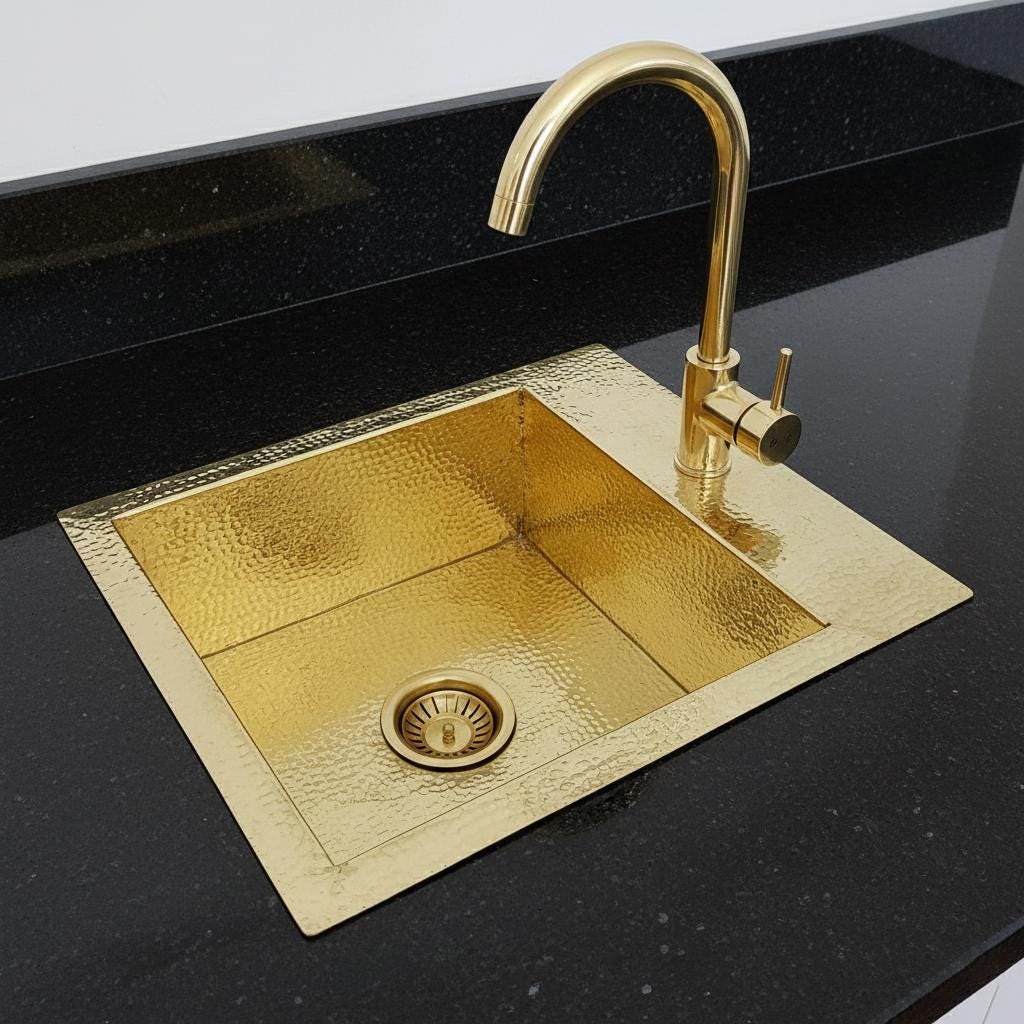 Gold kitchen sink with faucet on a black countertop