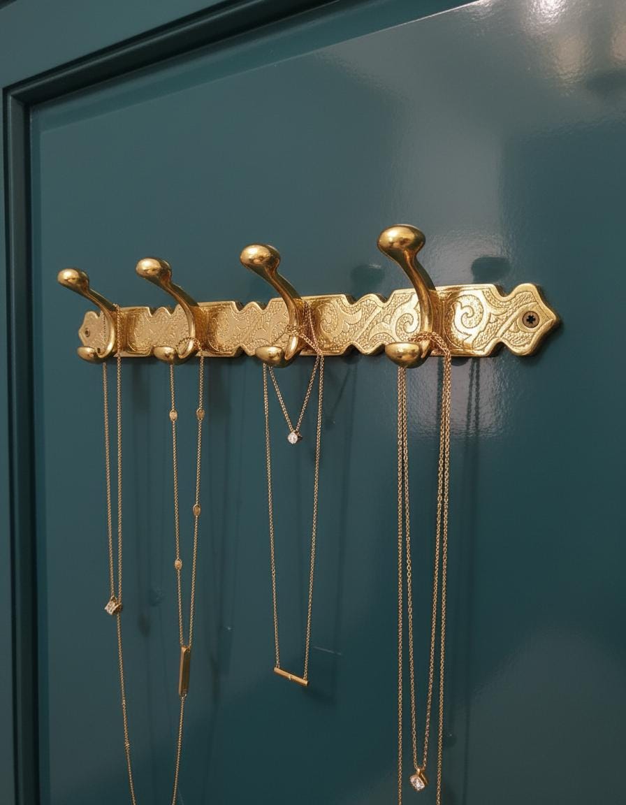 Gold jewelry holder with necklaces against a teal wall