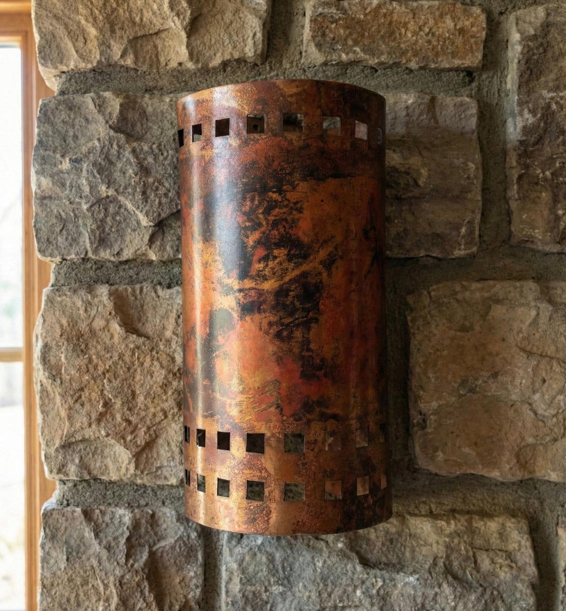 Cylindrical copper wall sconce on a stone wall