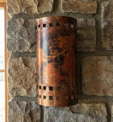 Cylindrical copper wall sconce on a stone wall