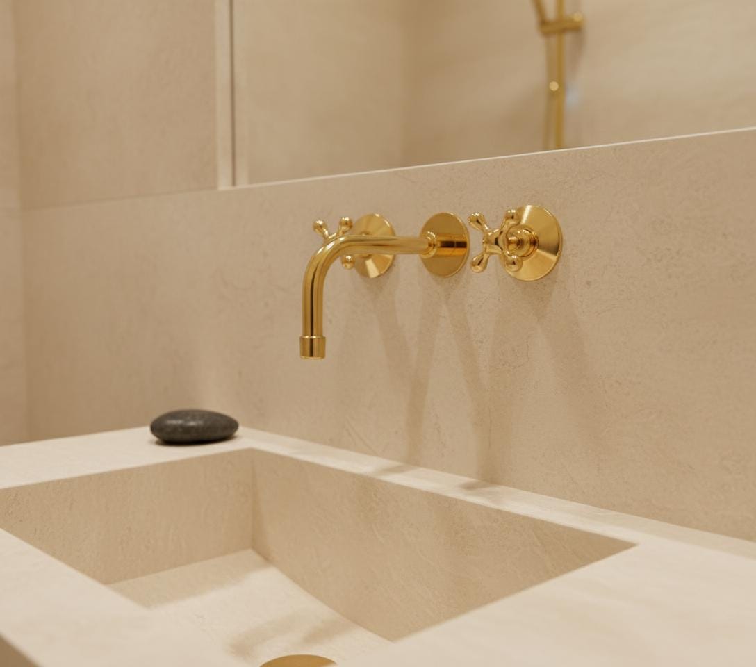 Gold faucet on a beige tiled wall above a sink.