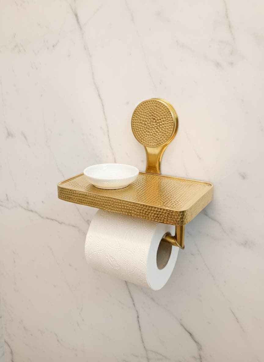 Gold toilet paper holder with a bowl on a marble wall