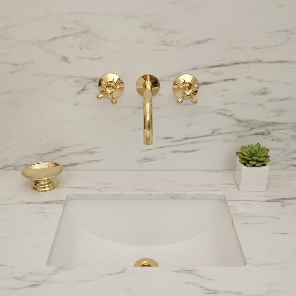 Gold faucet on a white sink with floral wallpaper in the background