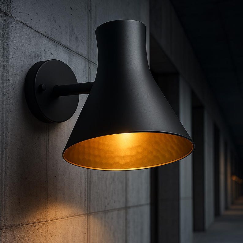 Handcrafted black wall sconce with hammered brass glow – artisan-made luxury fixture

