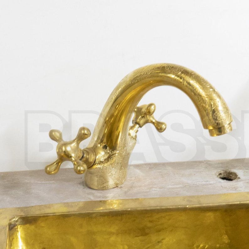 Handmade Moroccan brass bathroom faucet with engraved detail, dual handles, and gooseneck spout. Unlacquered brass ages with rich patina.

