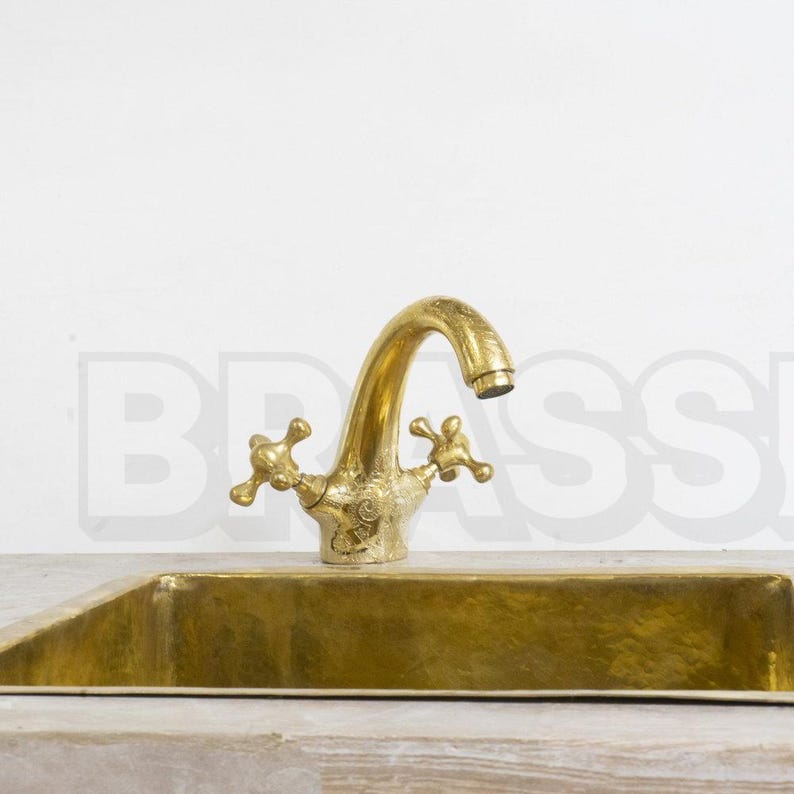 Handmade Moroccan brass bathroom faucet with engraved detail, dual handles, and gooseneck spout. Unlacquered brass ages with rich patina.

