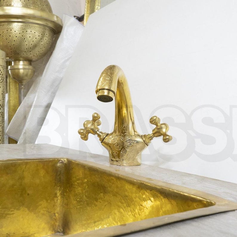 Handmade Moroccan brass bathroom faucet with engraved detail, dual handles, and gooseneck spout. Unlacquered brass ages with rich patina.

