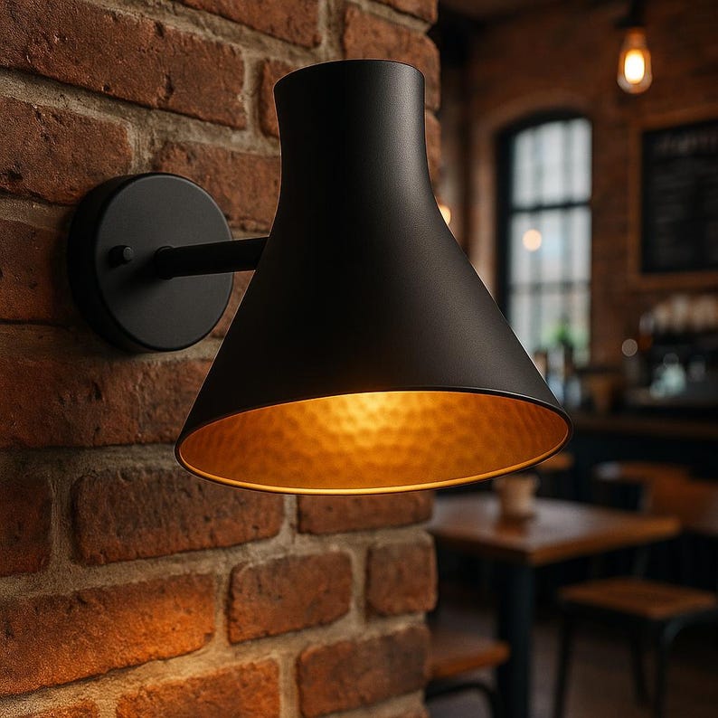 Handcrafted black wall sconce with hammered brass glow – artisan-made luxury fixture

