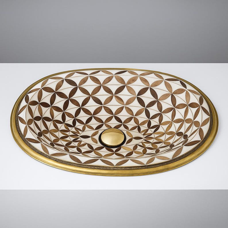Handmade oval brass bathroom sink with bone and wood floral inlay on white base

