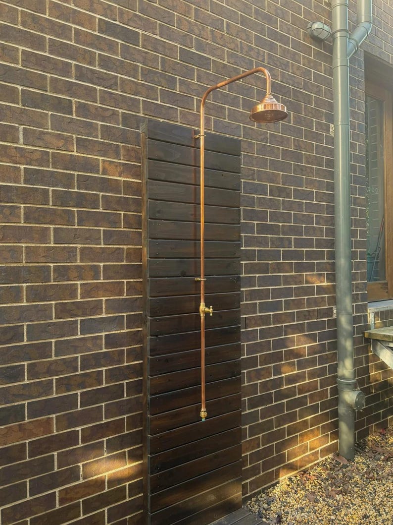 Minimalist copper and brass outdoor shower with natural patina finish

