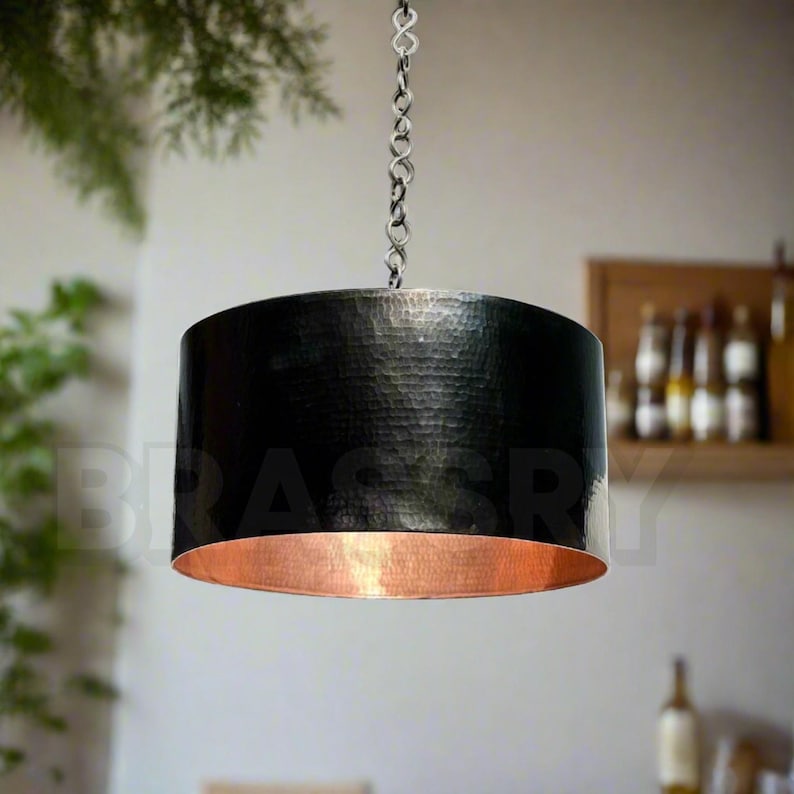 Handcrafted Moroccan black copper drum pendant light hanging over a dining table

