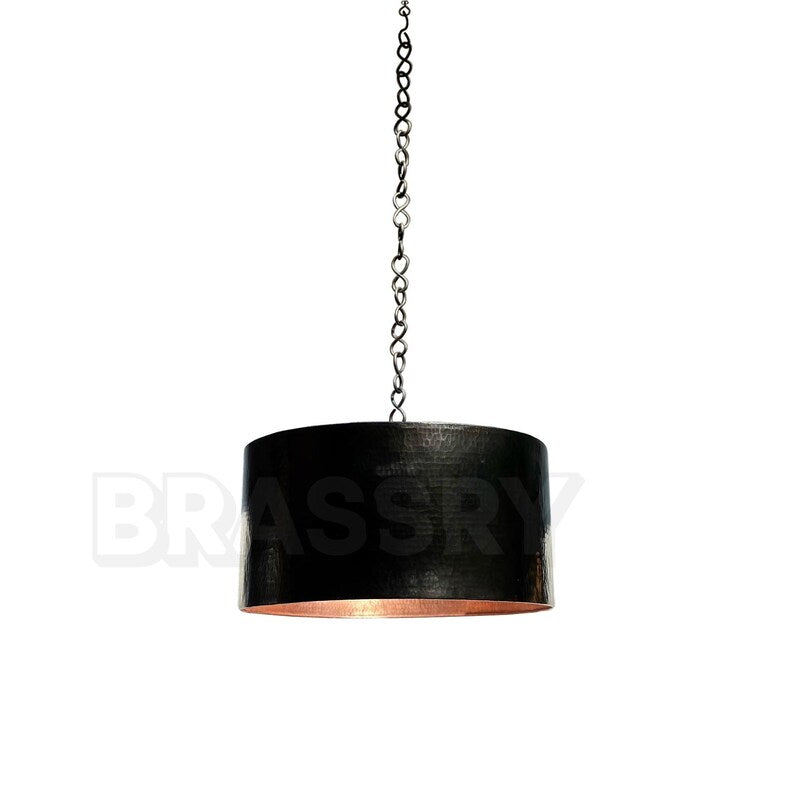 Handcrafted Moroccan black copper drum pendant light hanging over a dining table

