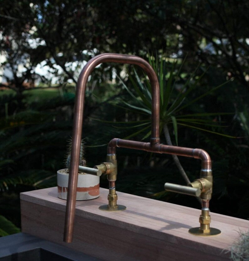 Rustic handmade copper faucet with dual hot and cold brass handles

