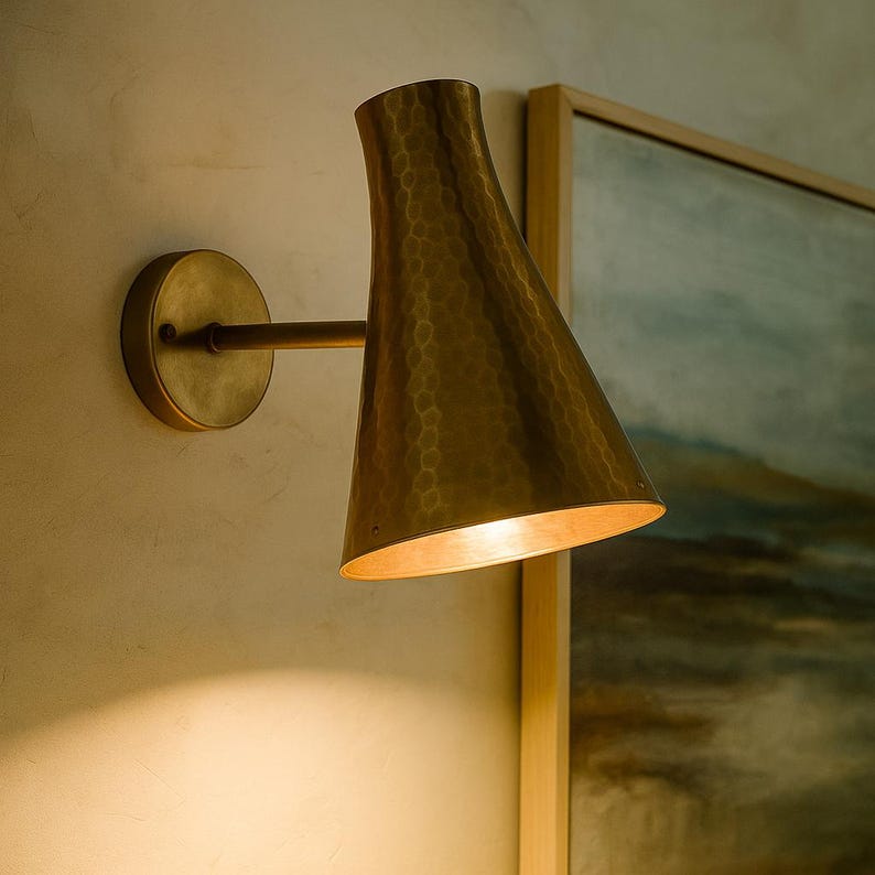 Rustic modern brass wall light with hammered texture and cone shape

