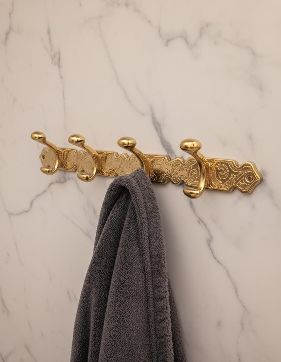 Decorative gold hook with a gray towel on a marble wall