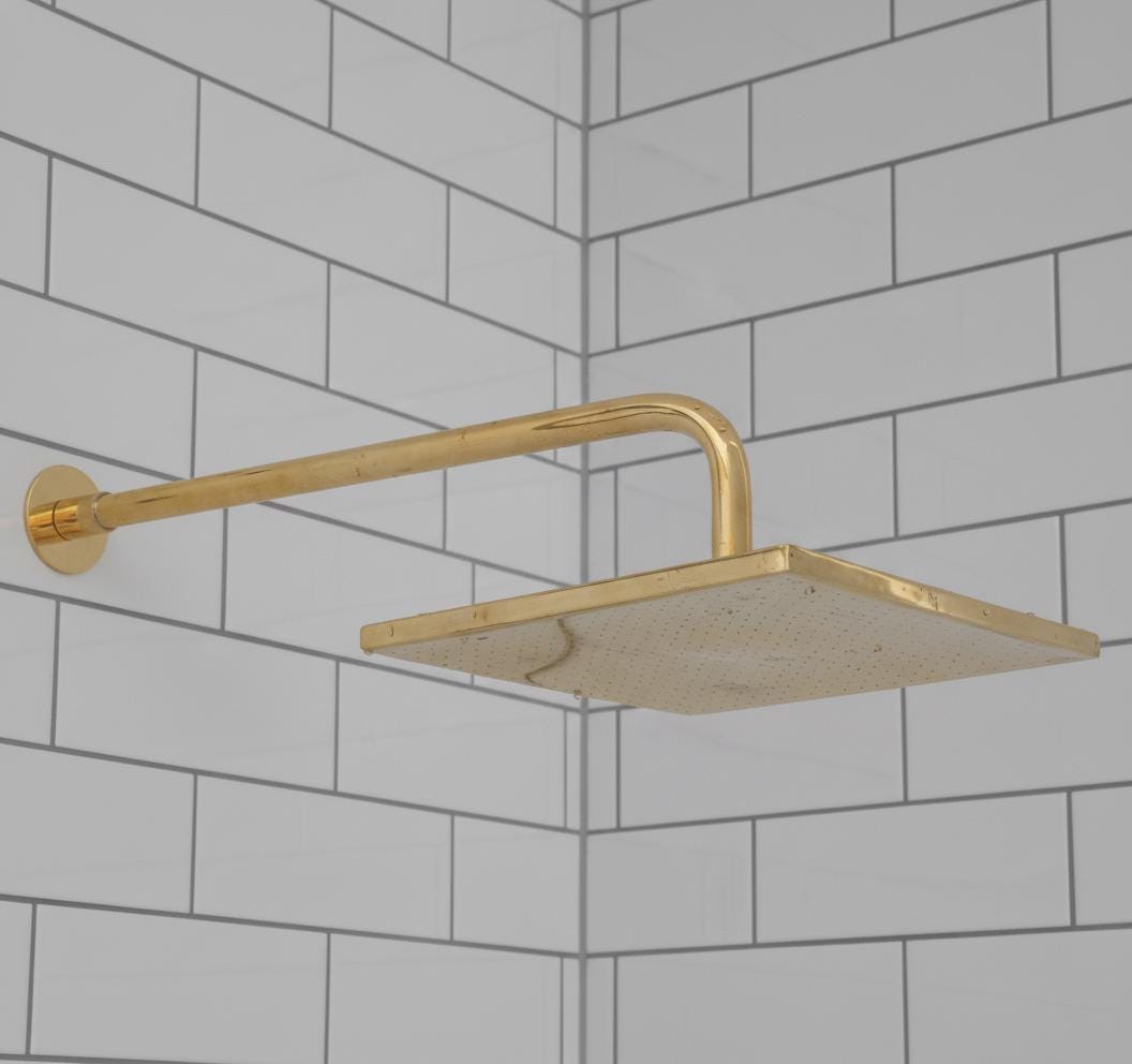 Gold shower head mounted on a tiled bathroom wall