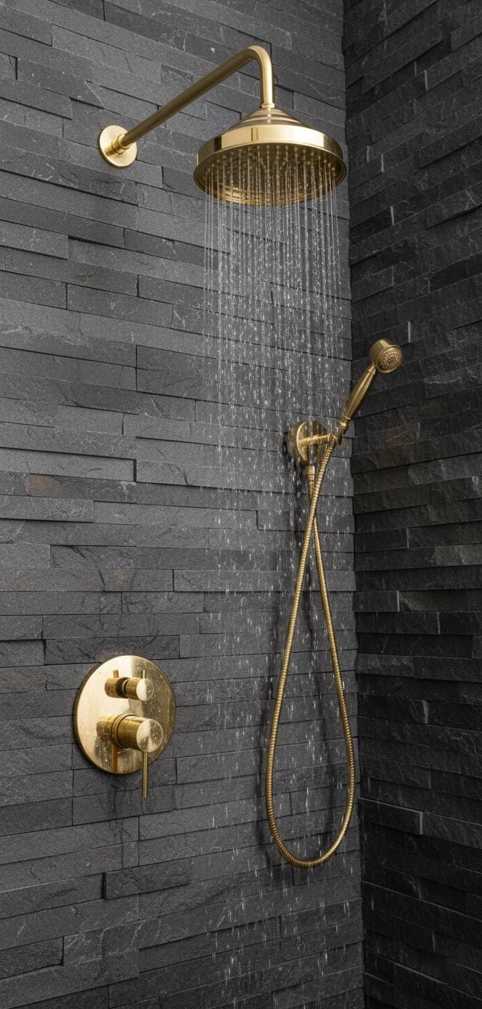 Gold shower head and control panel mounted on a dark stone wall.
