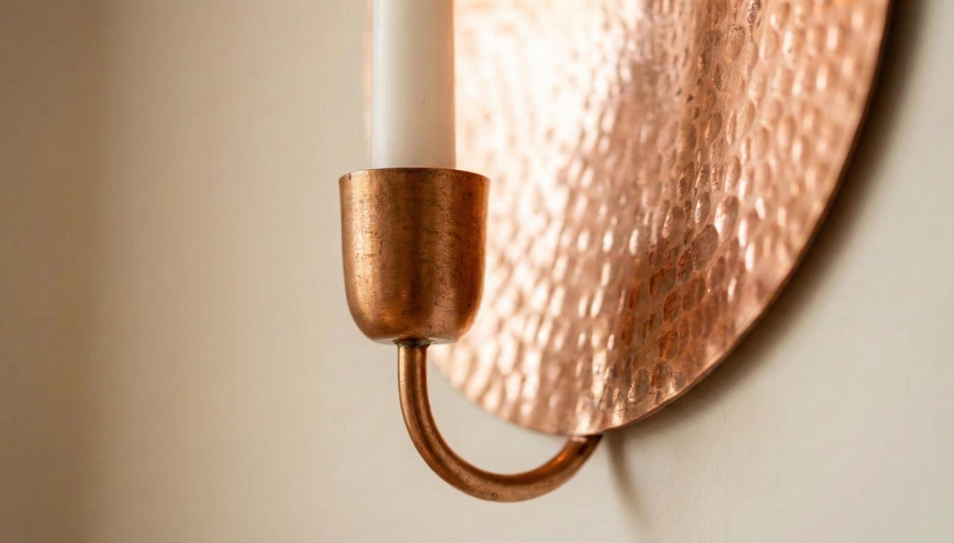 Copper wall sconce with a candle on a neutral background