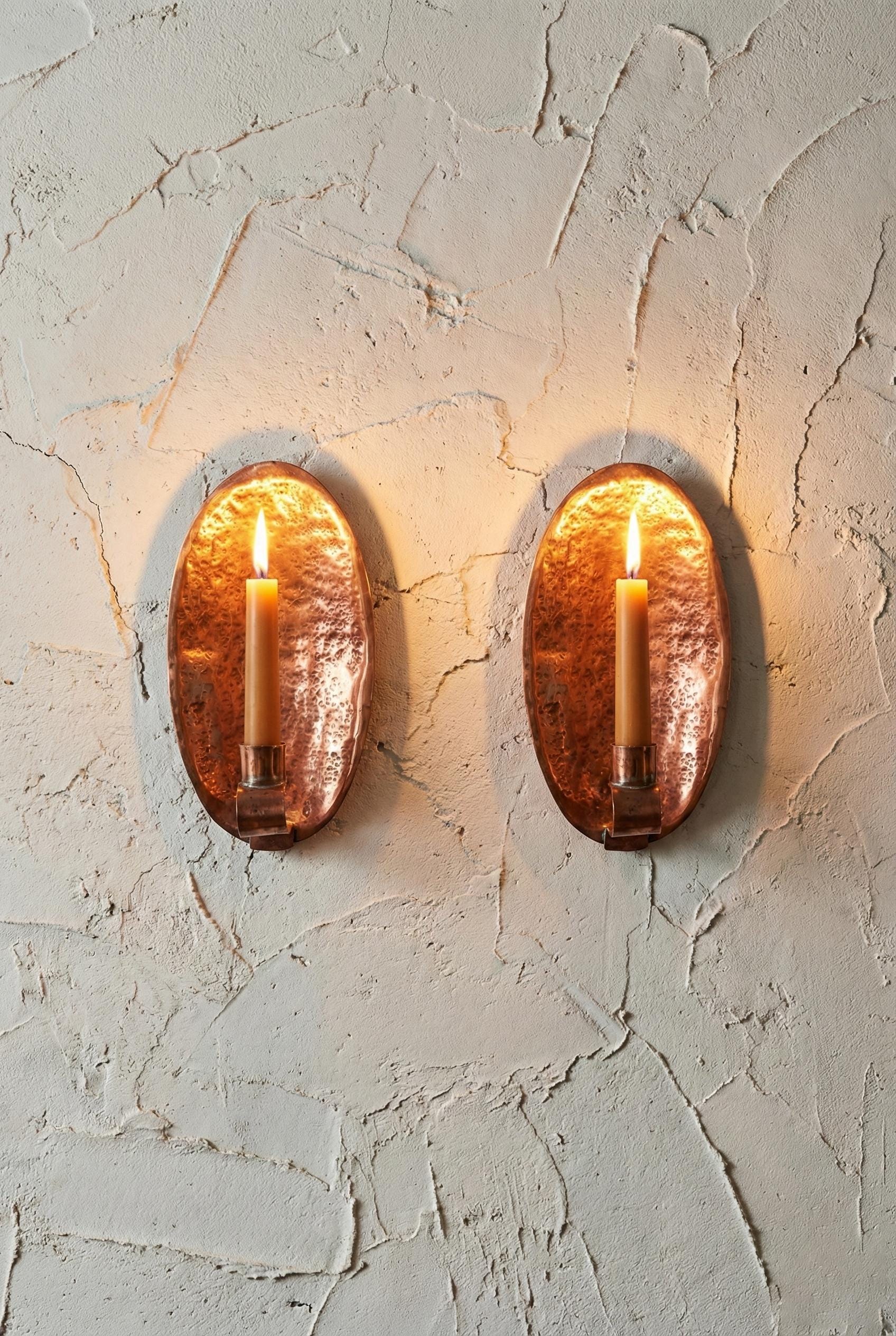 Two oval wall sconces with a warm glow on a textured wall.