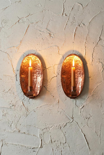 Two oval wall sconces with a warm glow on a textured wall.