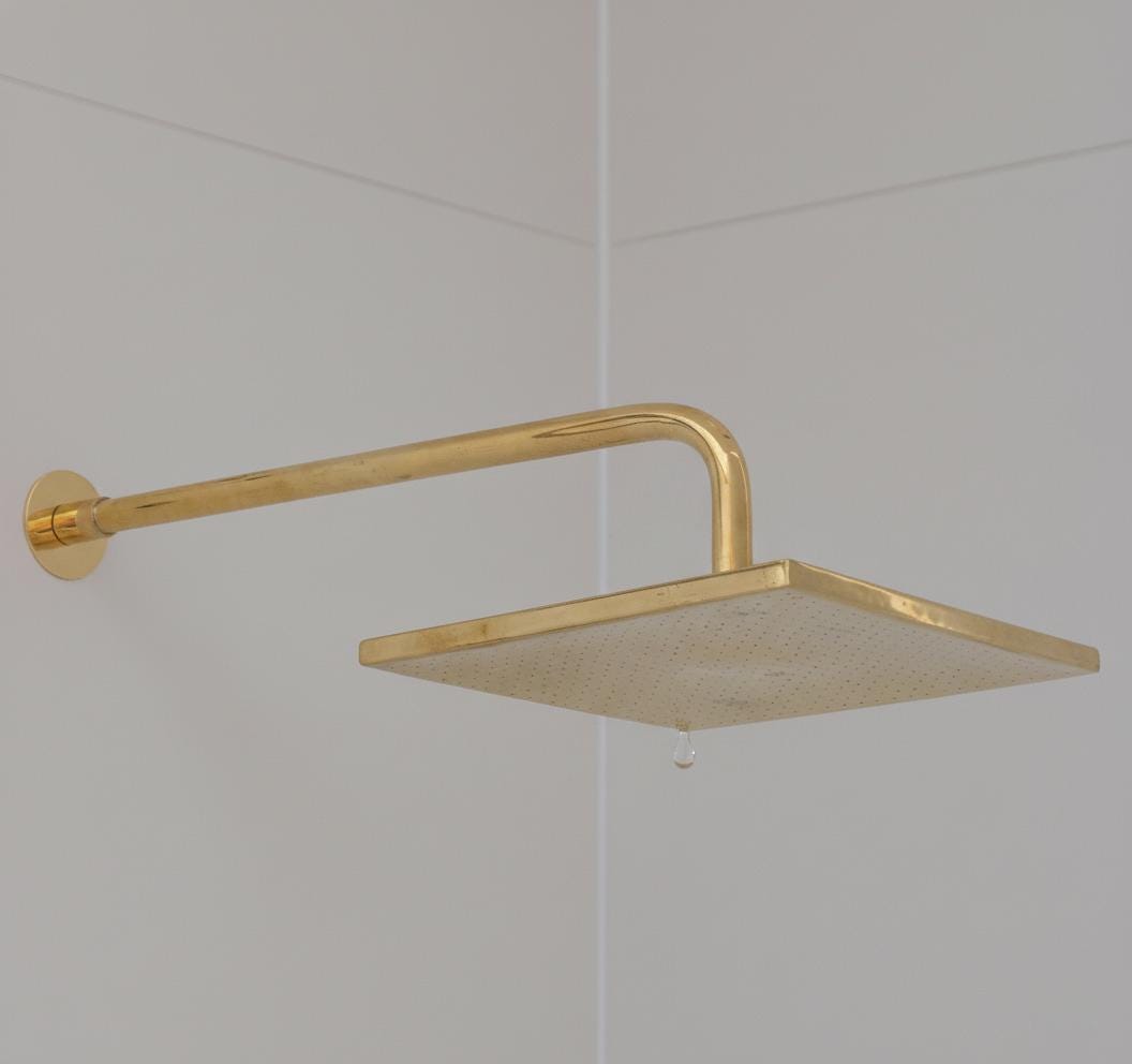 Gold shower head mounted on a tiled wall