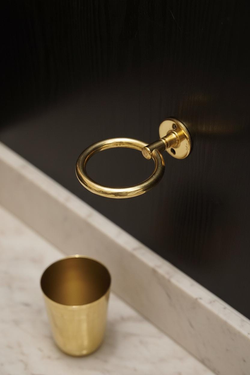 Gold towel ring and cup on a black surface with marble base