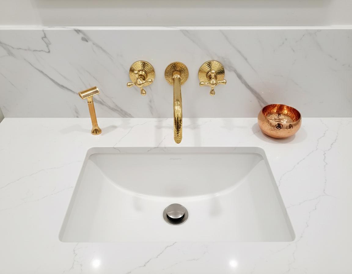 Gold faucet and handles on a white sink with marble background