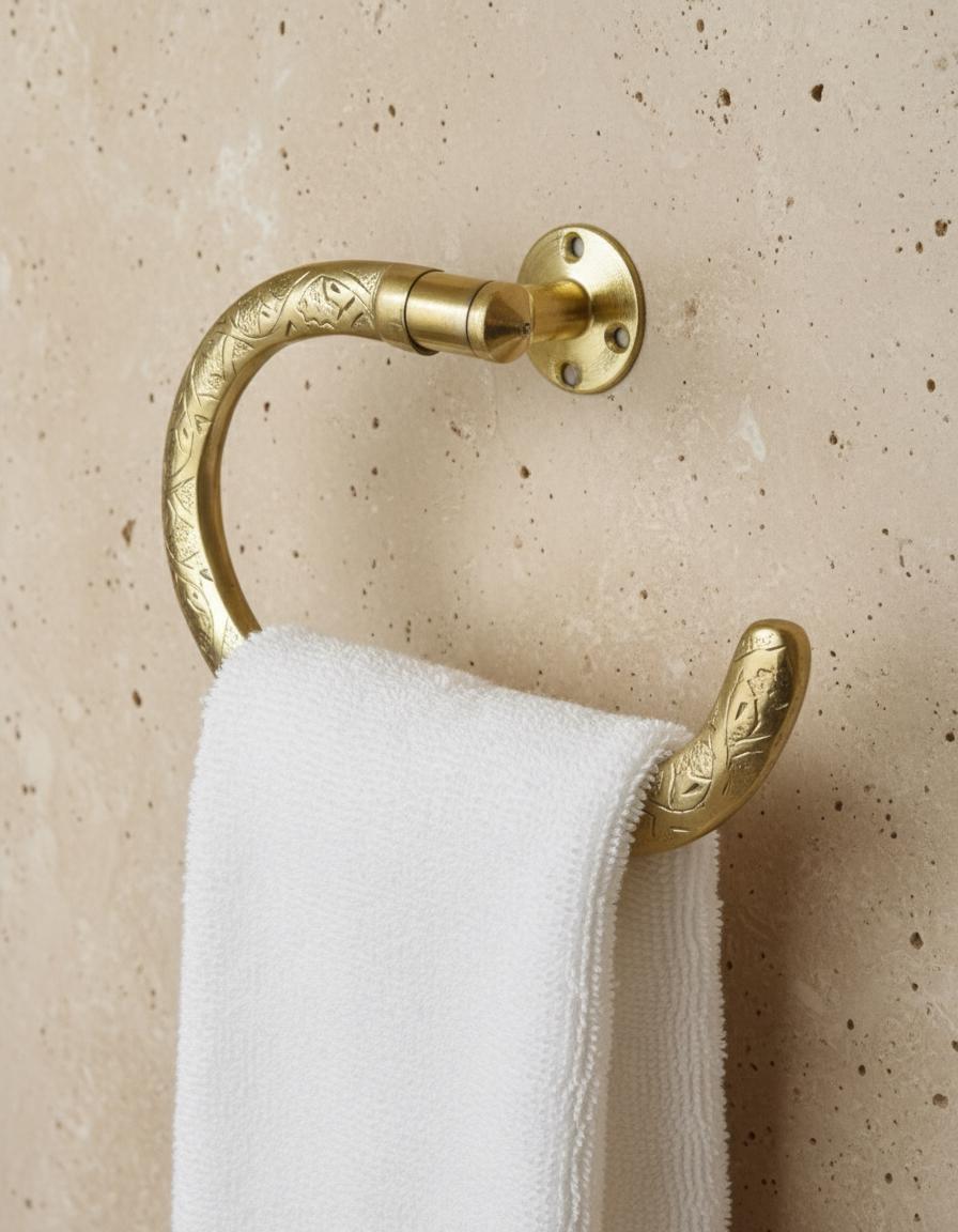 Gold towel ring with a white towel on a beige wall