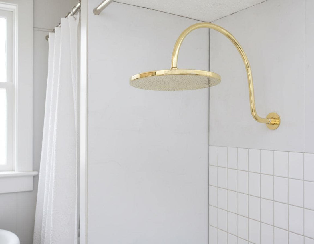 Gold shower head mounted on a tiled bathroom wall