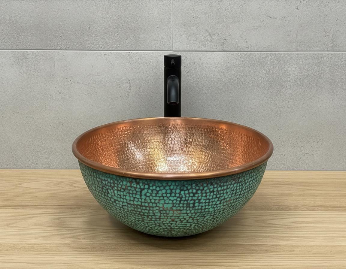 Copper and turquoise patterned sink on a wooden surface with a gray tiled wall background