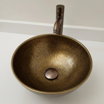 Bronze sink with faucet on a white countertop