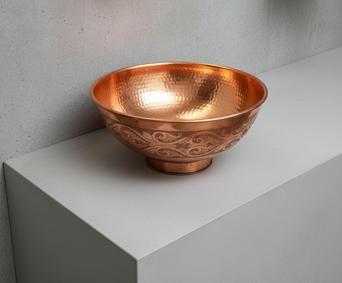 Copper bowl with intricate patterns on a light gray surface.