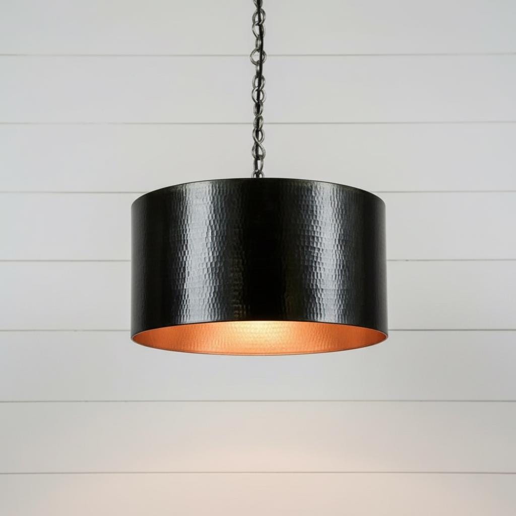 Black pendant light with a copper interior on a white wooden background